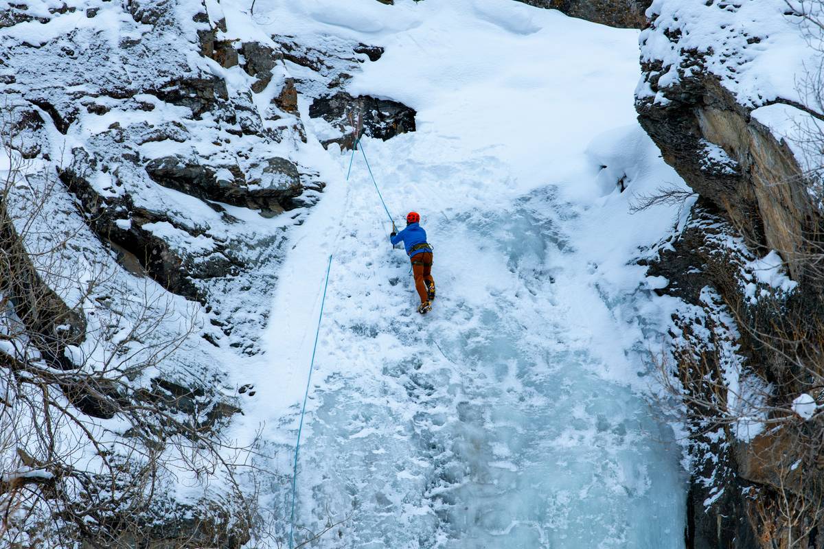 Climber wearing helmet with Snow and Ice Adaptations on icy ridge at dawn